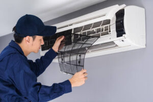 Air Specialties technician changing air filter in indoor air conditioning unit.