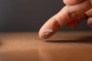 Finger picking up dust as it glides through dusty surface